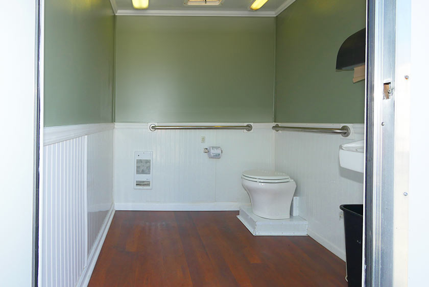 TOILET, VANITY WITH SINK AND MIRROR INSIDE THE LIBERTY RESTROOM TRAILER