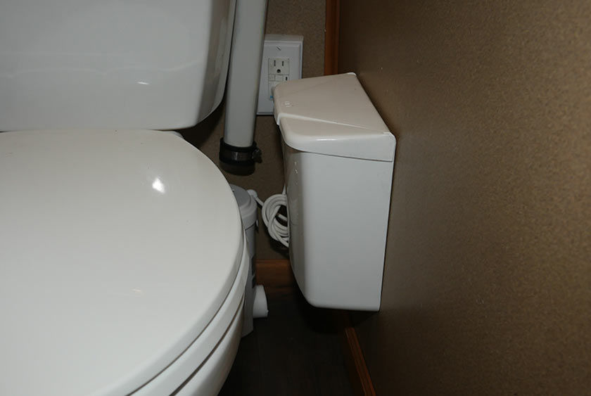 WALL MOUNTED COVERED TRASH RECEPTACLE NEXT TO TOILET BOWL