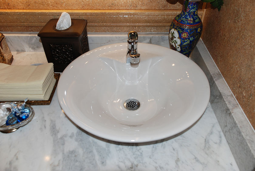 PORCELAIN VESSEL SINKS NESTLED ATOP A RICH CALCUTTA MARBLE SLAB